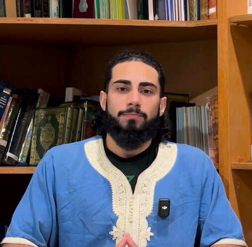 Hamza Aurangzeb, sitting in front of a bookshelf